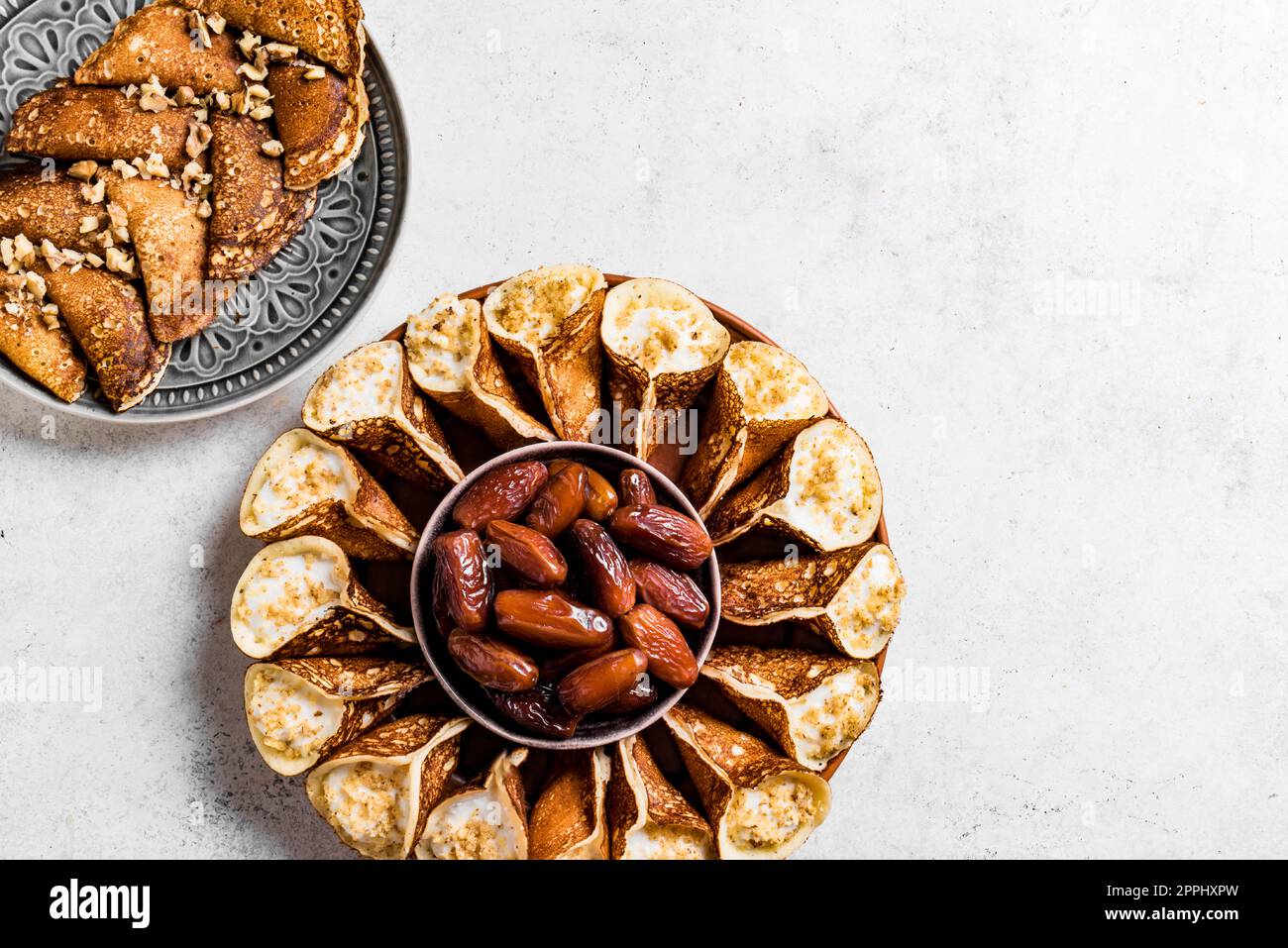 Postre iftar árabe del Medio Oriente qatayef o atayef, pastelería rellena en forma de media luna con nueces en blanco, espacio de copia. Cocina árabe. Foto de stock