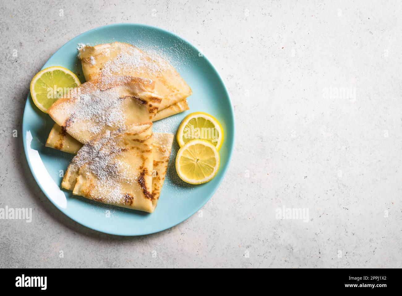 Cítricos crepes Suzette con limón sobre fondo blanco, espacio de copia. Crepes caseros para el desayuno o el postre. Foto de stock