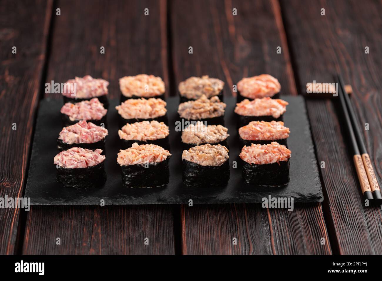 Conjunto de Gunkan Maki Sushi con diferentes tipos de salmón de pescado, vieira, perca, anguila, camarones y caviar sobre fondo de mesa de madera. Menú de sushi. Comida japonesa sushi set gunkans Foto de stock