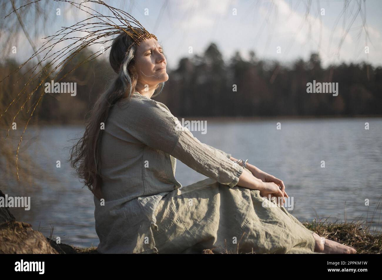 Cierre la mujer en traje pagano eslavo sentado en la imagen del retrato de la costa del lago Foto de stock