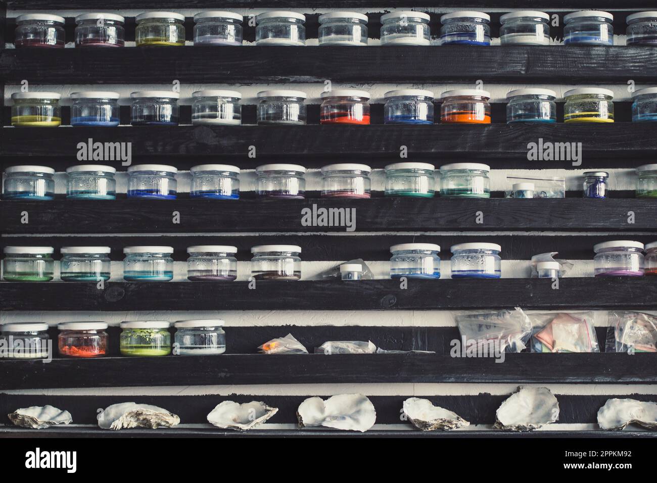 Cierre filas de estantes con frascos de pintura de vidrio y conchas de mar concepto foto Foto de stock