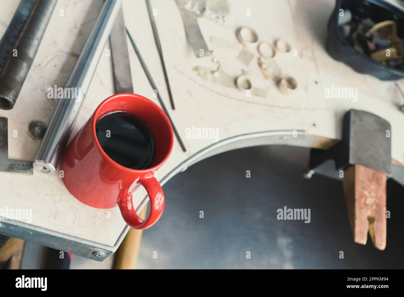 Cierre la taza roja con el café que coloca en la foto del concepto de la mesa del taller Foto de stock