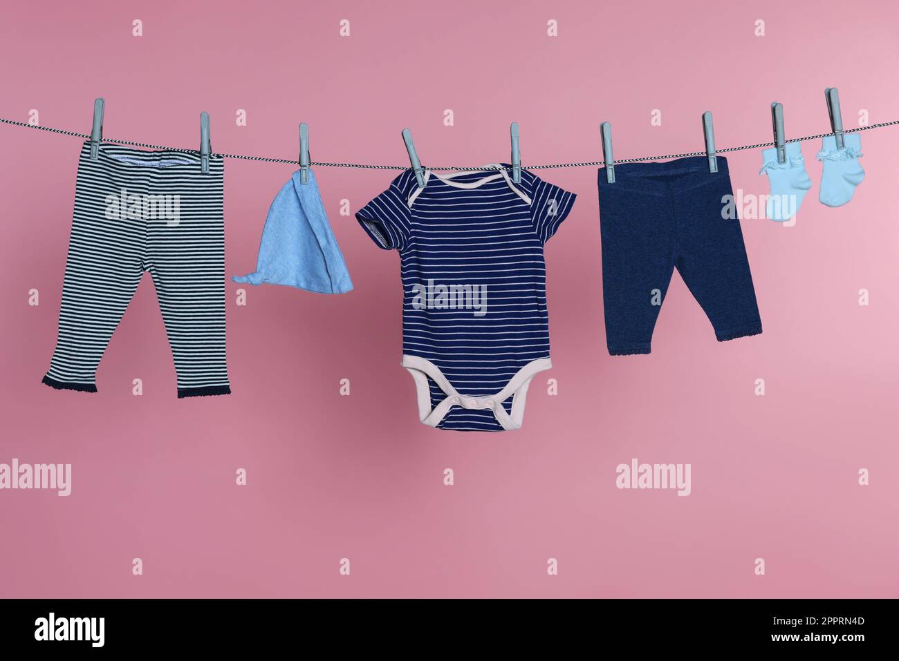 Ropa de bebé diferente que se seca en la línea de lavandería contra el  fondo rosa Fotografía de stock - Alamy