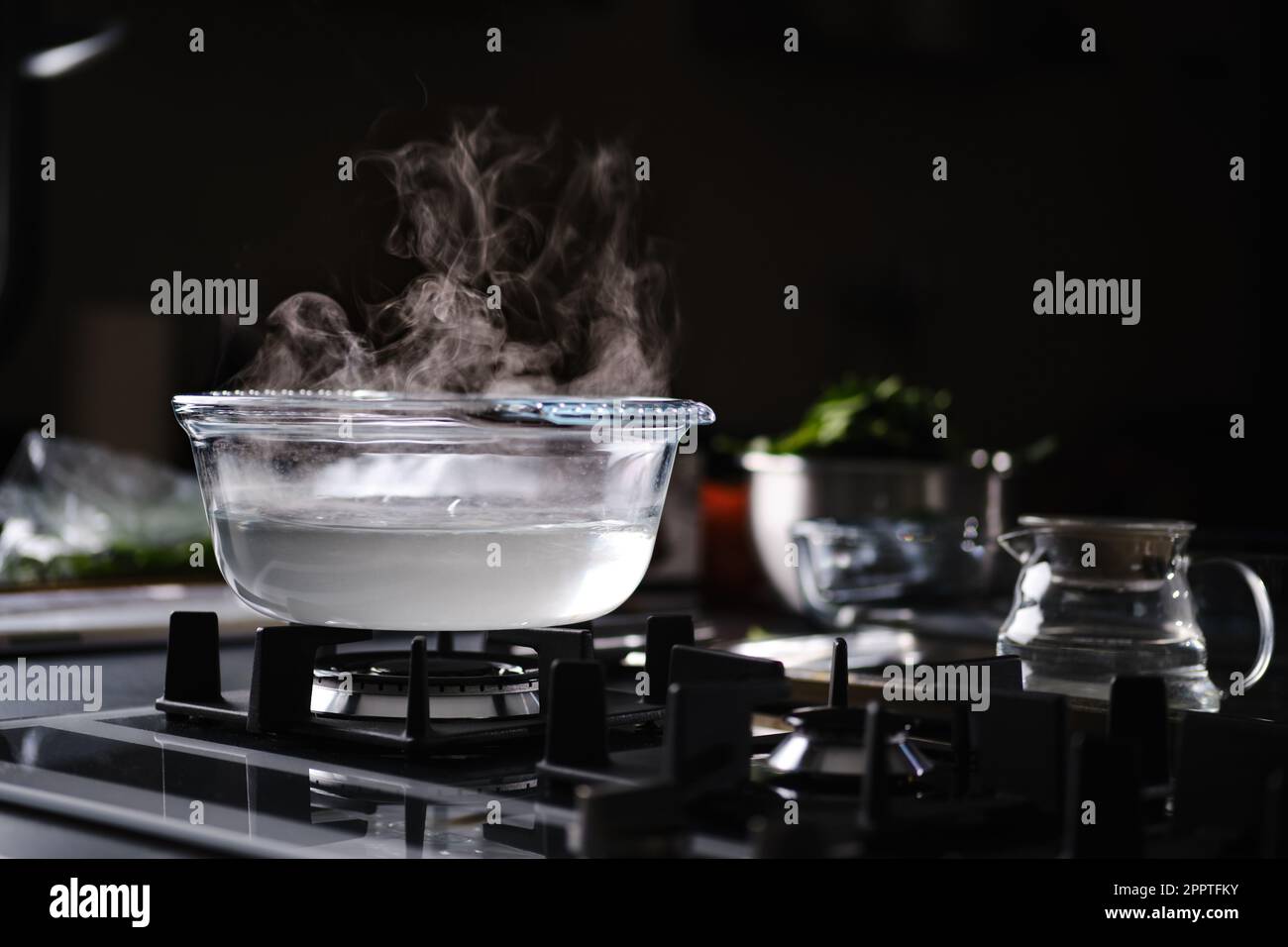 Agua caliente en olla transparente en estufa de gas Foto de stock