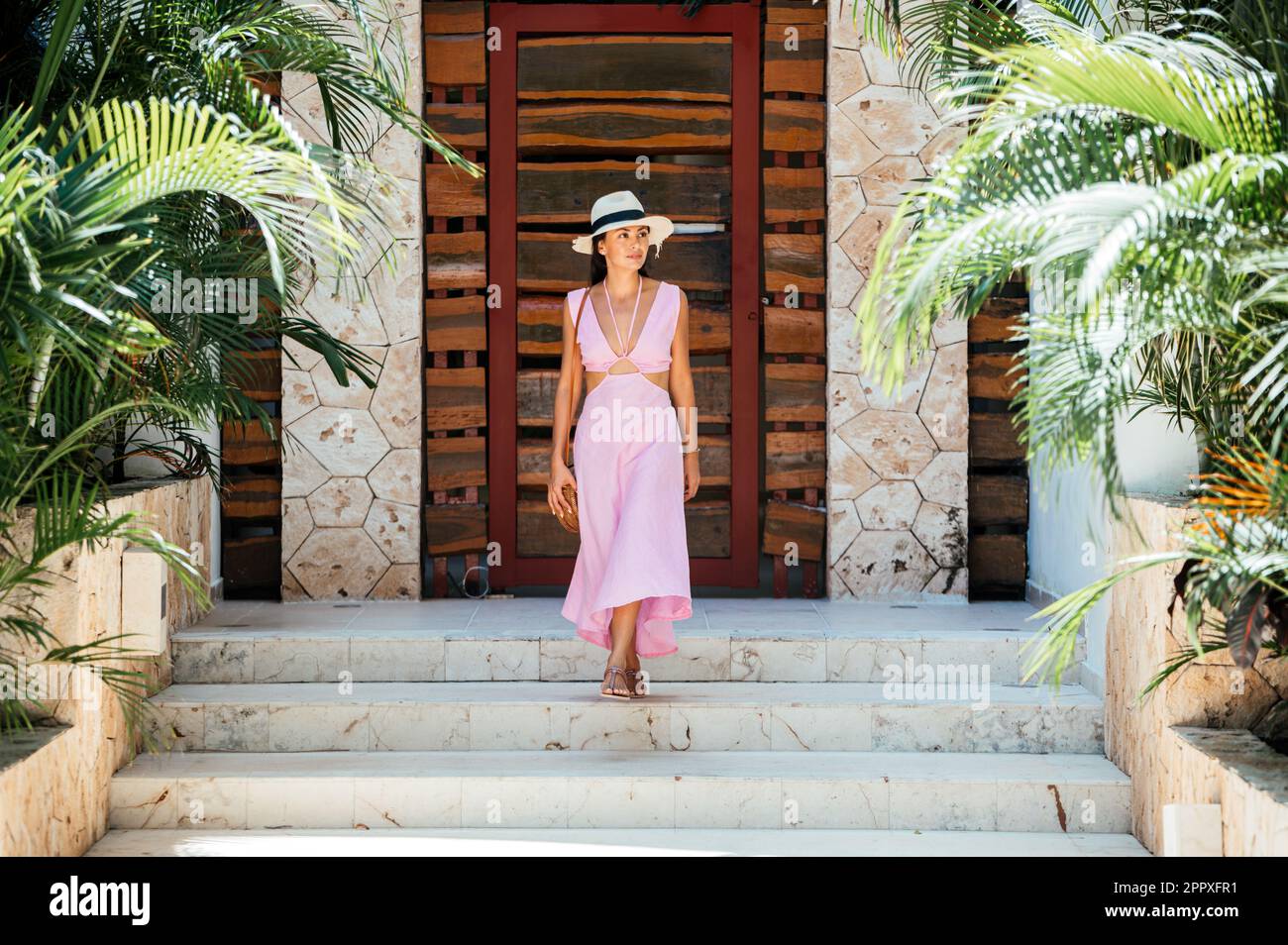 Cuerpo completo de turista japonesa mexicana joven pensativa en vestido  maxi rosa y sombrero de paja mirando hacia otro lado mientras bajaba en el  soleado resort Fotografía de stock - Alamy