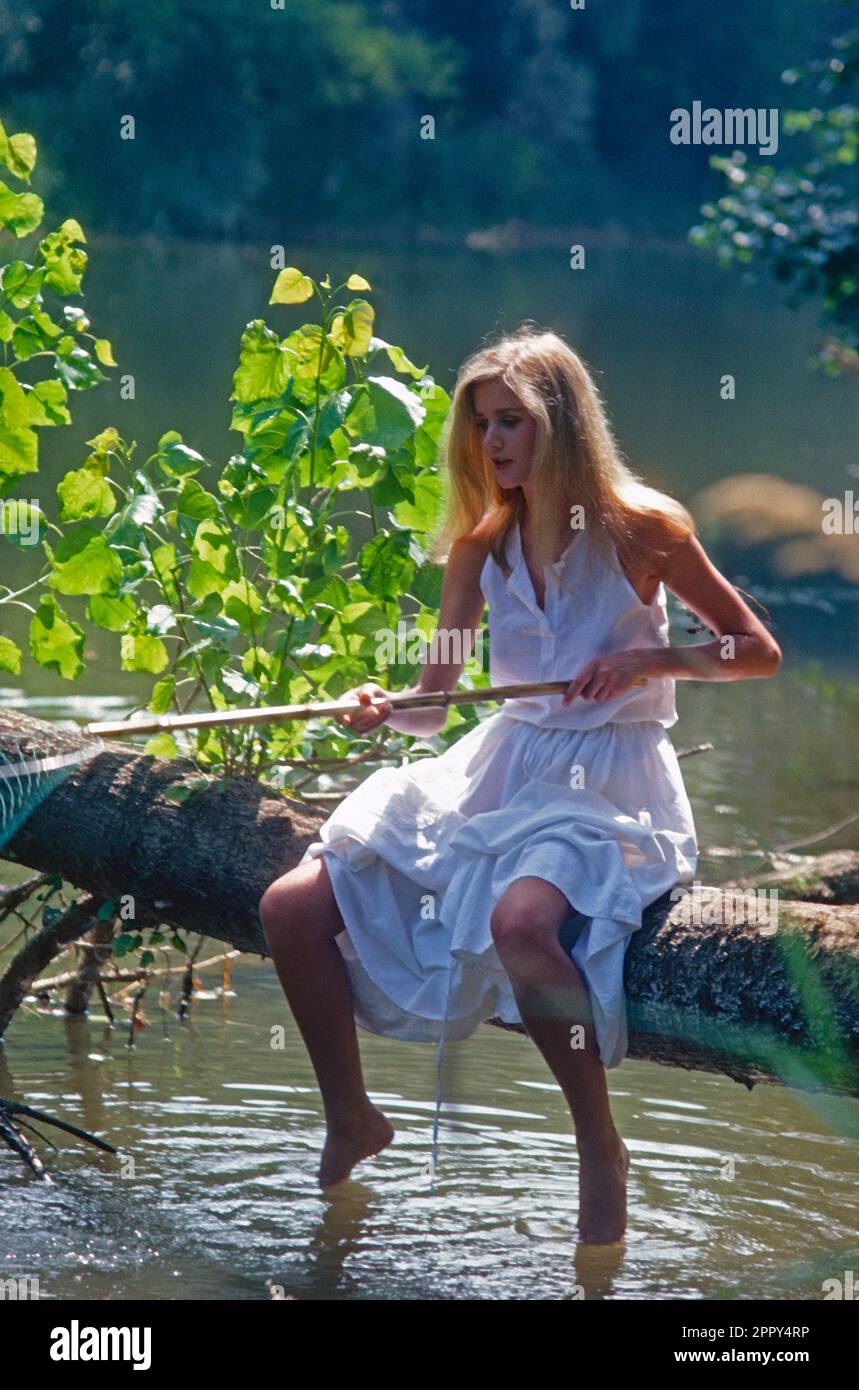 Francia. Dordoña. Mujer joven que se sienta en la rama del árbol sobre el río. Foto de stock