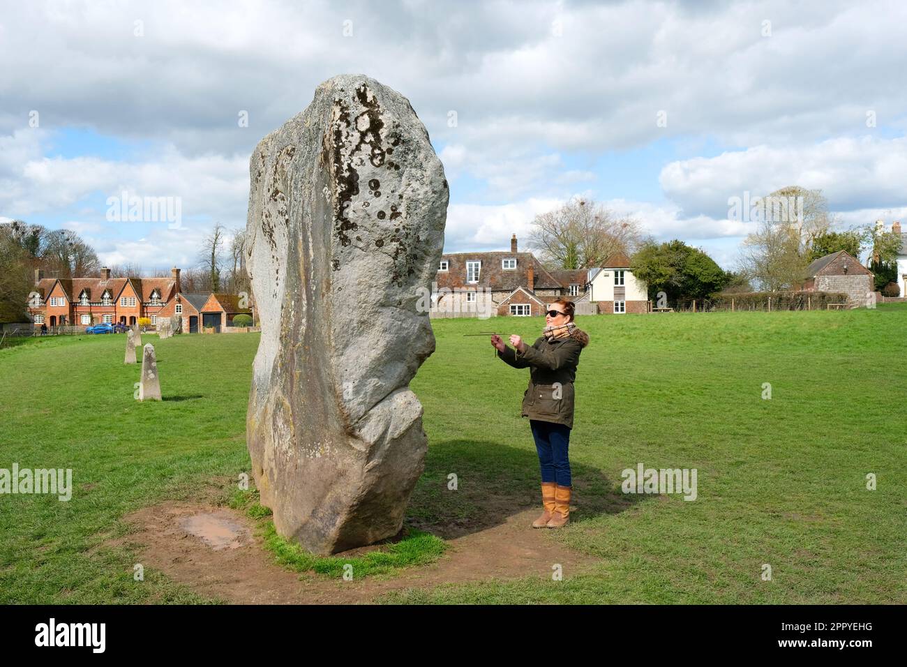Mujer que captura las energías de la tierra en el círculo de piedra de Avebury, Wiltshire, Reino Unido - John Gollop Foto de stock