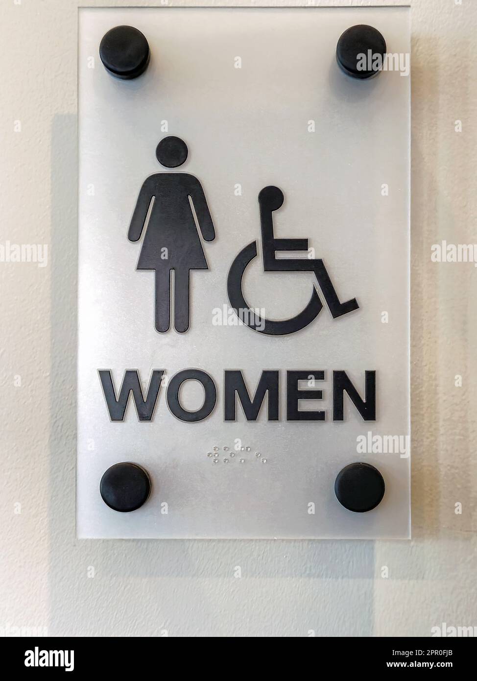 Primer plano de un letrero de baño de vidrio para mujer con función de braille Foto de stock
