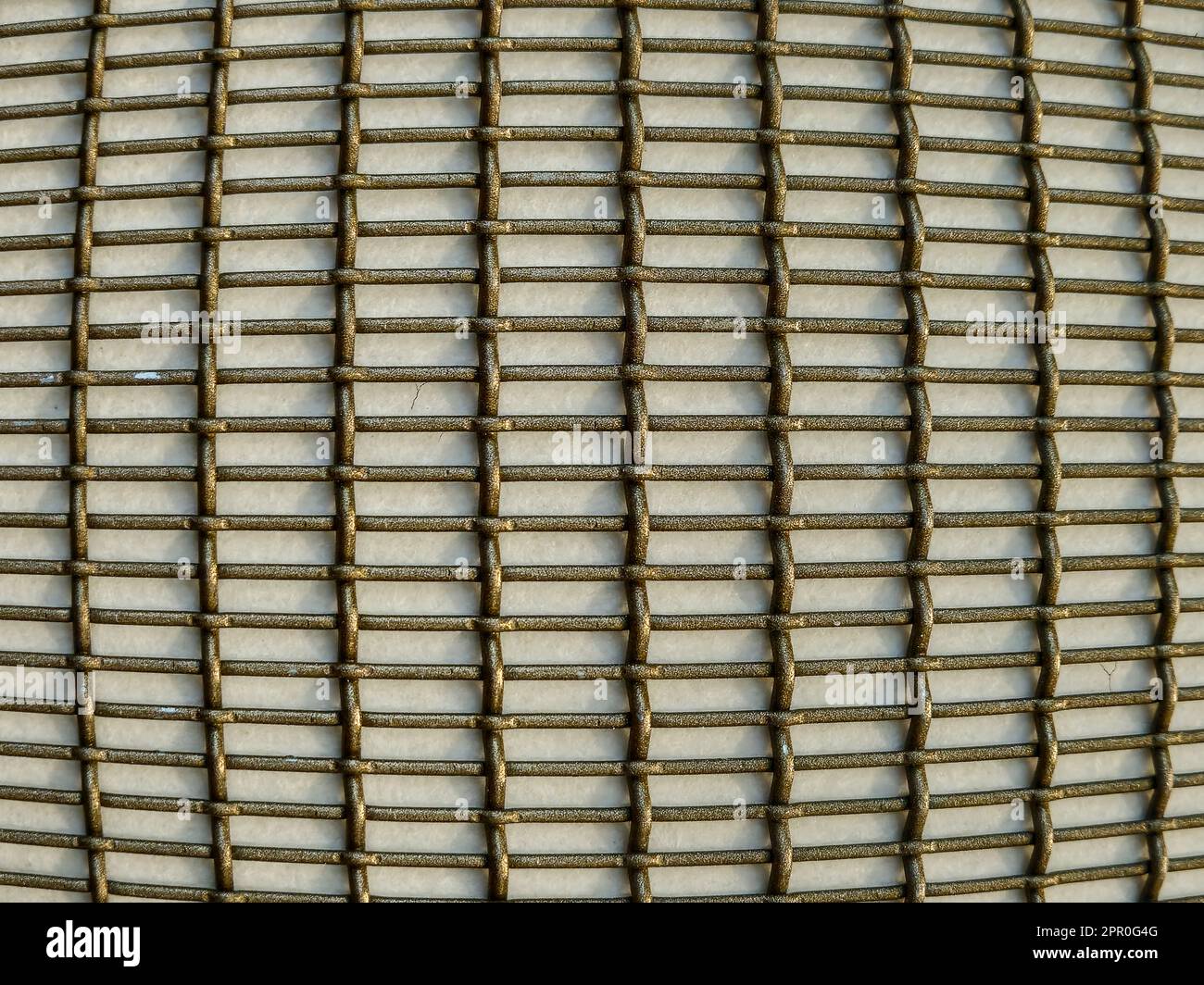 Primer plano de un patrón de rejilla metálica de bronce convexo en una pared Foto de stock