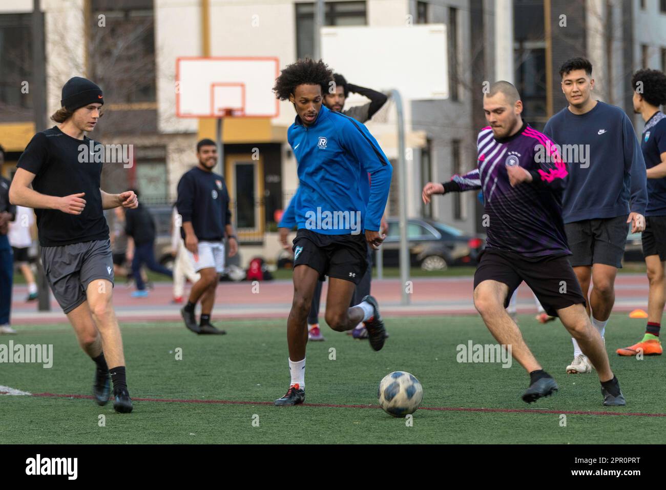 Los jugadores de varias razas y etnias disfrutan de un juego armonioso de fútbol en el redesarrollado barrio Regent Park de Toronto Foto de stock
