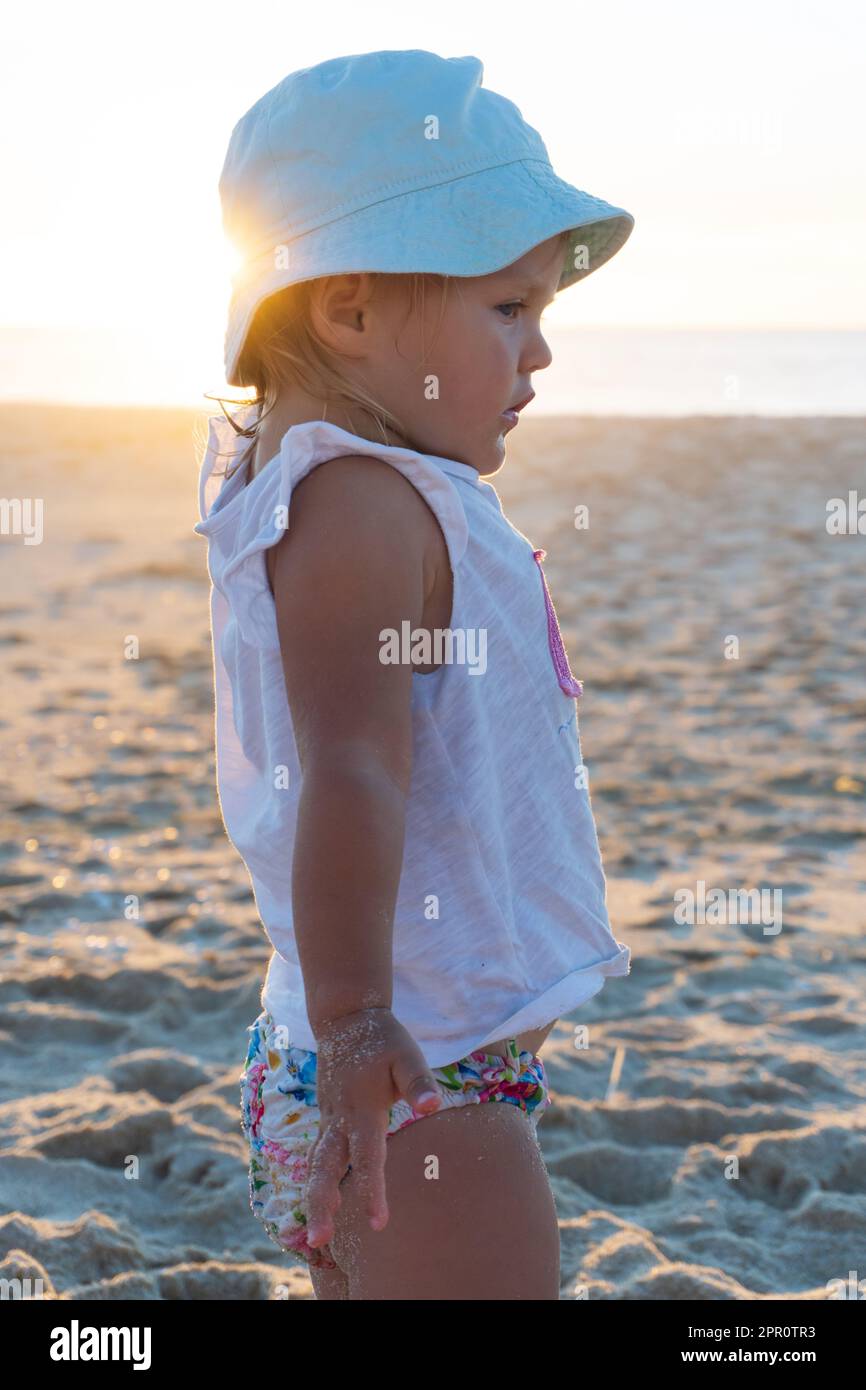 Niña rubia en un sombrero de panamá está de pie con la espalda en la playa  y mira el océano Fotografía de stock - Alamy