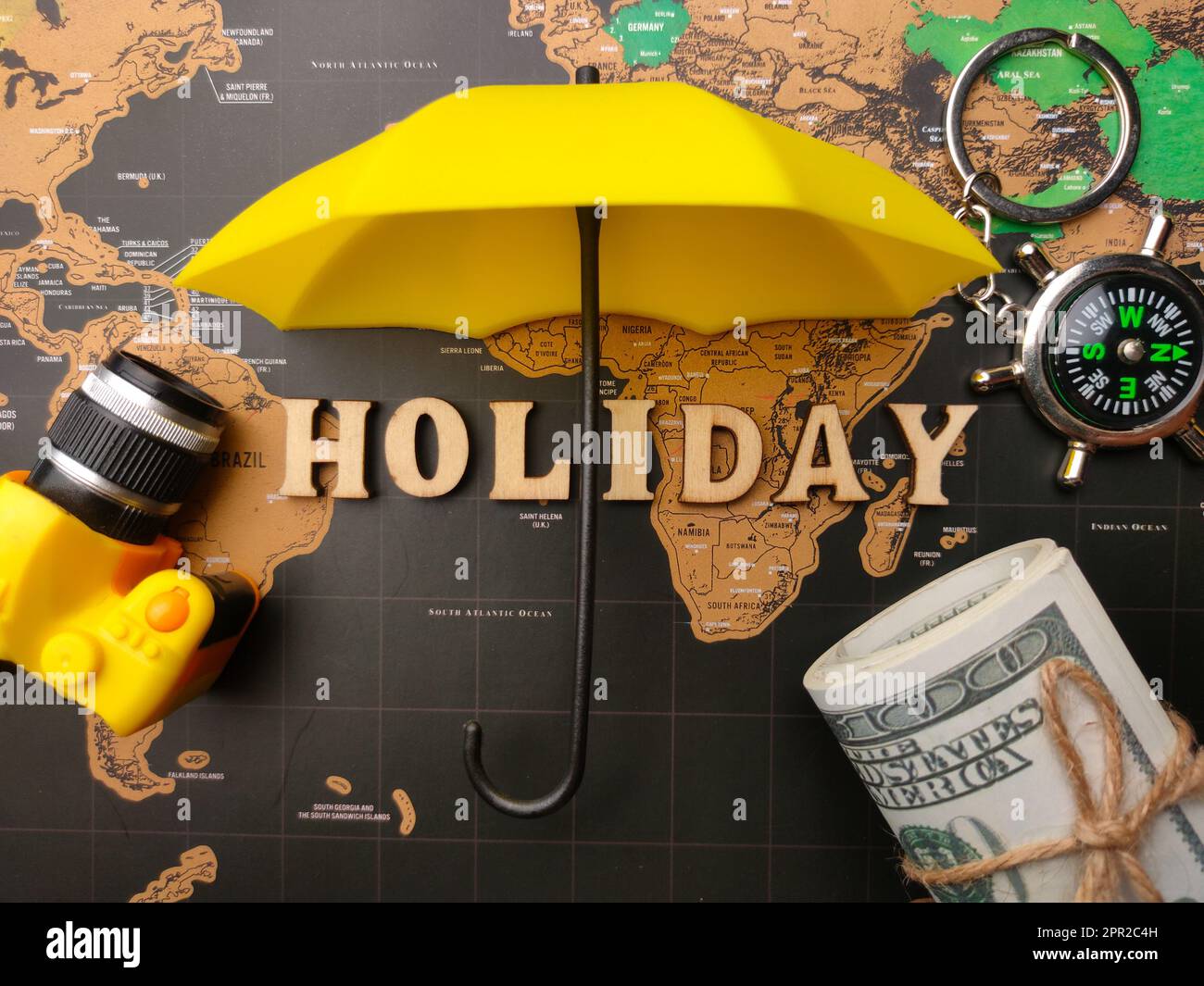 Paraguas, brújula y billetes con la palabra VACACIONES en un fondo de mapa  del mundo Fotografía de stock - Alamy
