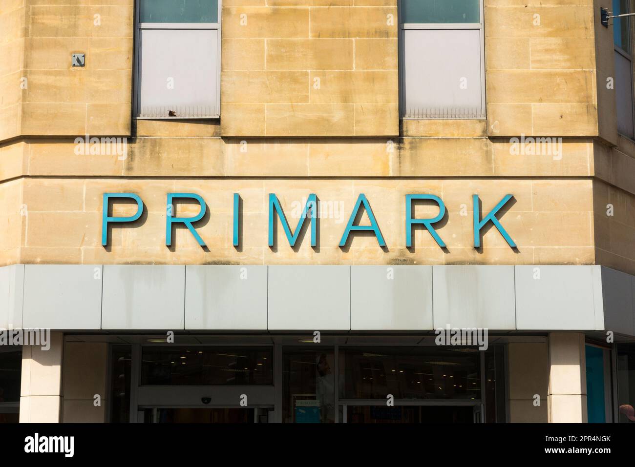 Letrero de la tienda Primark en la fachada de una tienda / entrada de un  outlet en la zona comercial del centro de la ciudad de la calle principal.  Balneario Cheltenham. Gloucestershire.