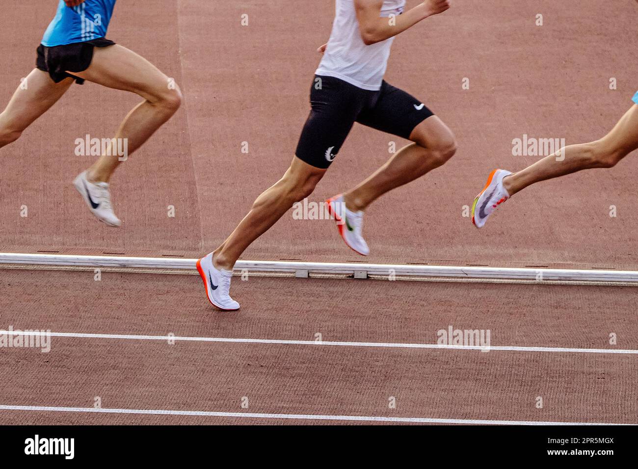 Piernas corredor masculino en zapatillas Nike Spikes media distancia corriendo en el estadio en campeonatos de atletismo de verano Foto de stock