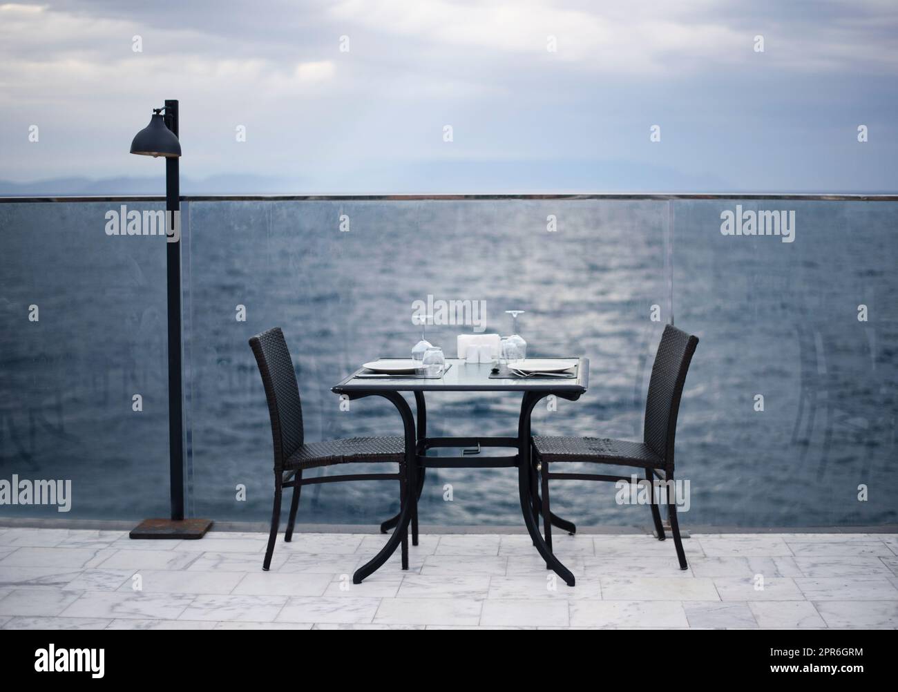 Increíble cena romántica en la playa. Romance y amor, mesa de comedor con vista al mar en el día nublado. Foto de stock