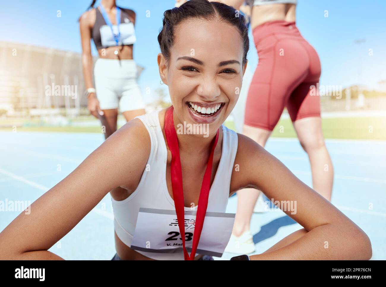 Primer retrato de mujer atlética de raza mixta con una medalla de competir en evento deportivo. Atleta latino activo en forma sonriente sintiéndose orgulloso después de ganar la carrera de running. Corredor de pista que logra el objetivo Foto de stock