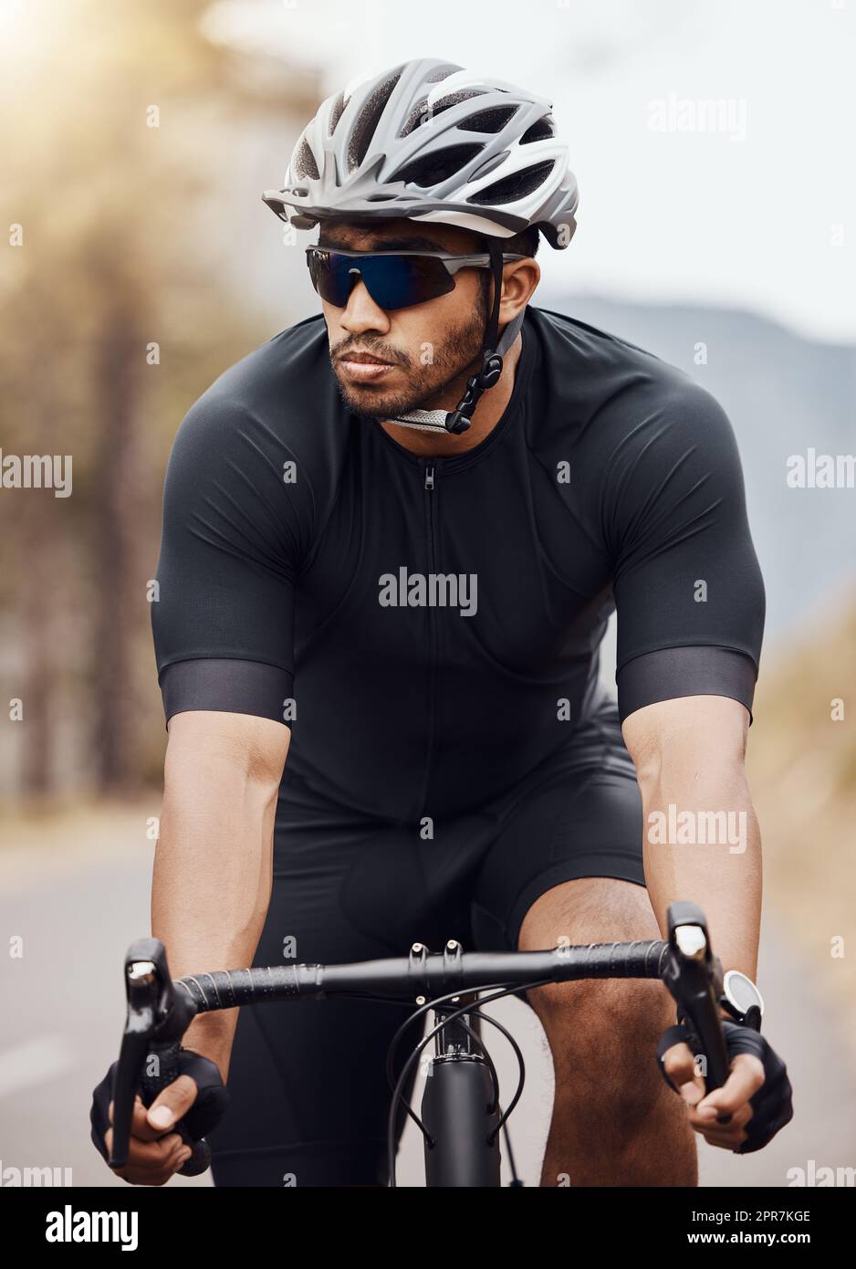 Hombre activo en ropa deportiva practicando ciclismo durante el día  soleado. deportista caucásico con casco de seguridad y gafas. actividad al  aire libre.