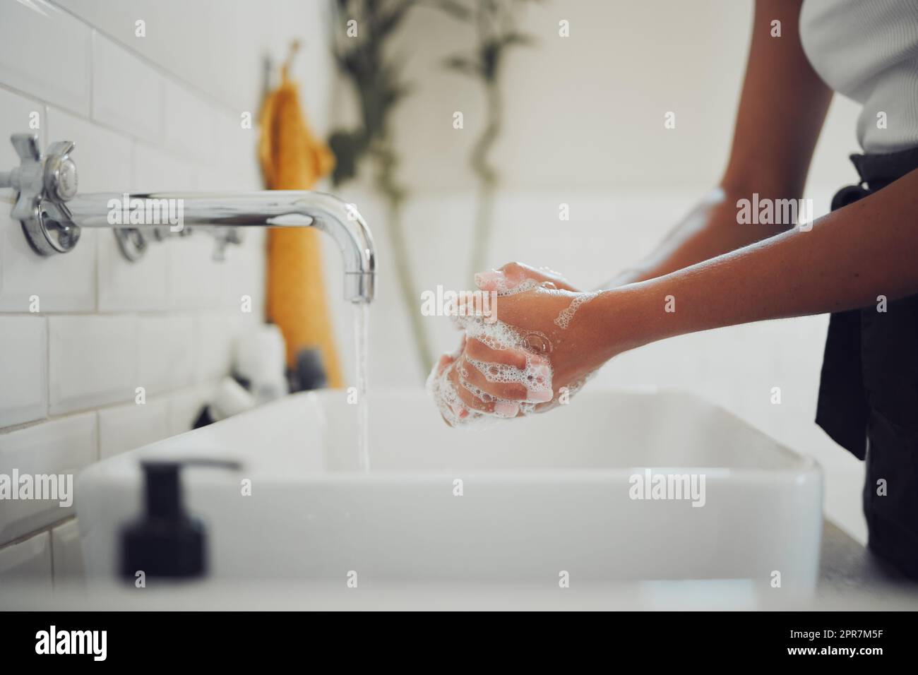 Cierre de las manos femeninas usando jabón y lavándose las manos bajo el grifo con agua limpia. Mujer frotándose las manos juntas antes de enjuagarse para la prevención del coronavirus Foto de stock