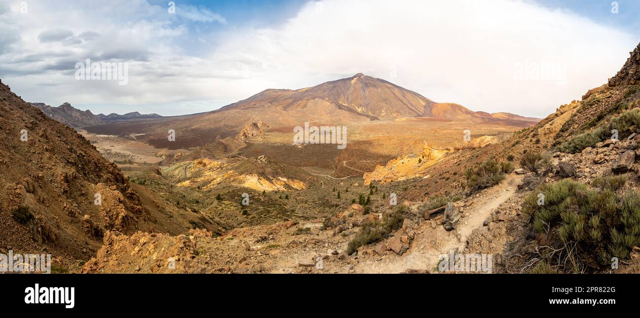 Una ruta de senderismo rodeada de paisajes volcánicos en el Parque Nacional del Teide que ofrece vistas panorámicas del amplio valle y el pico alto del volcán Teide. Foto de stock