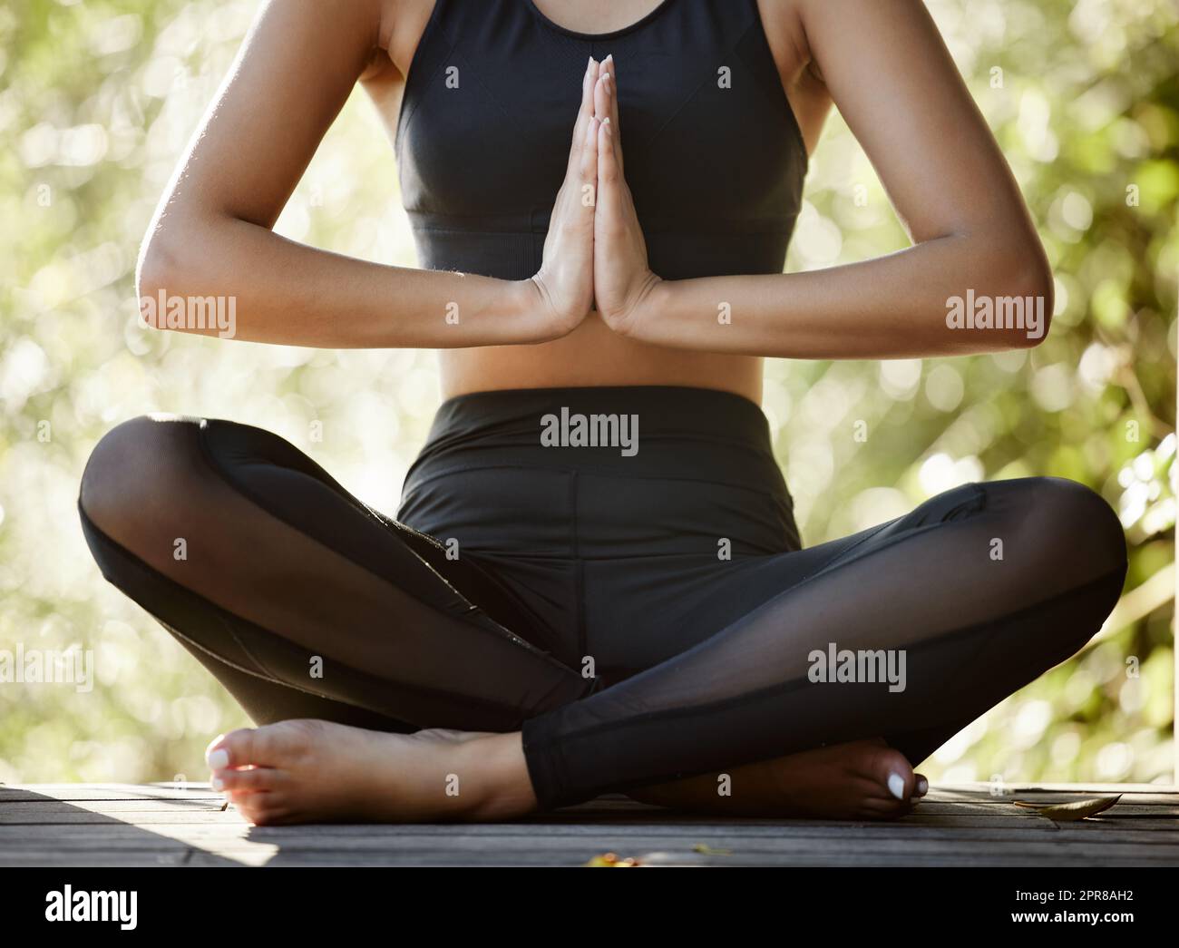 Ponga su mente a él. Fotografía recortada de una joven atleta irreconocible que meditaba mientras practicaba yoga al aire libre. Foto de stock