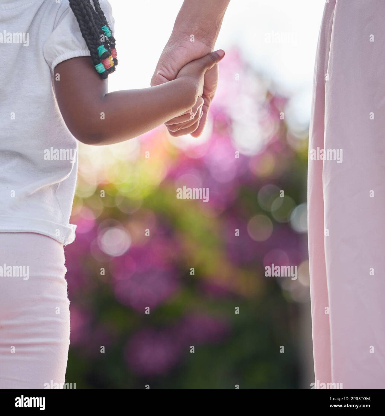 CloseUp madre e hija tomados de la mano mientras caminan afuera en el jardín. Un gran modelo a seguir y mentor para su niña. Una hija siempre mirará hacia arriba y seguirá los pasos de sus madres Foto de stock