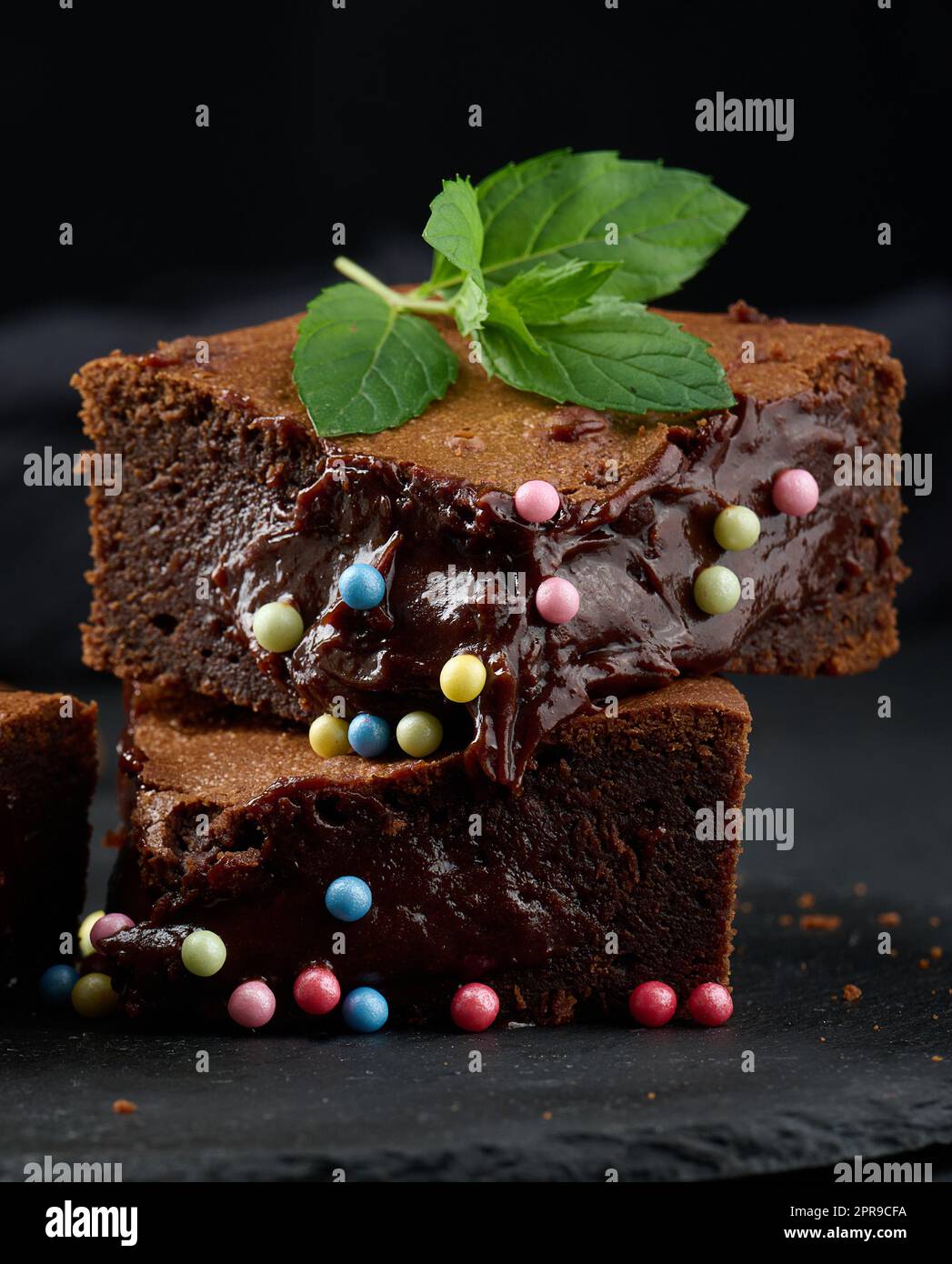 Trozos horneados de pastel de chocolate en una mesa negra Foto de stock