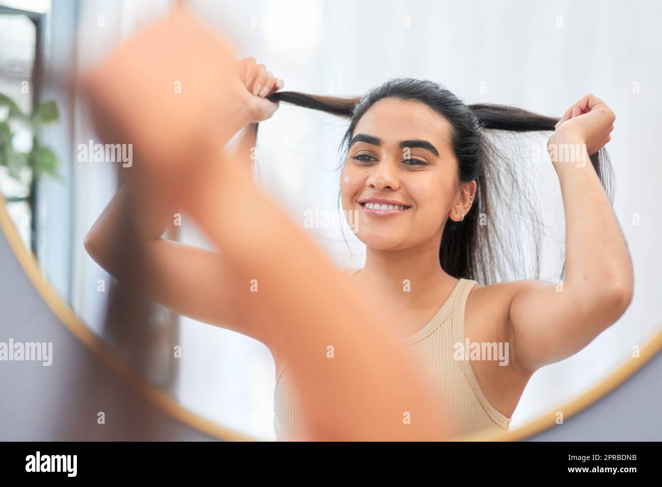 Pon tu cabello en una cola de caballo y prepárate para matar. una mujer  sonriendo mientras mira en el espejo del baño Fotografía de stock - Alamy