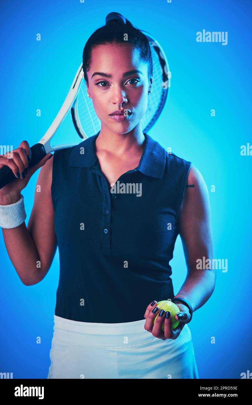 El tenis es el juego que me encanta. Retrato recortado de una atractiva jugadora de tenis posando sobre un fondo azul. Foto de stock