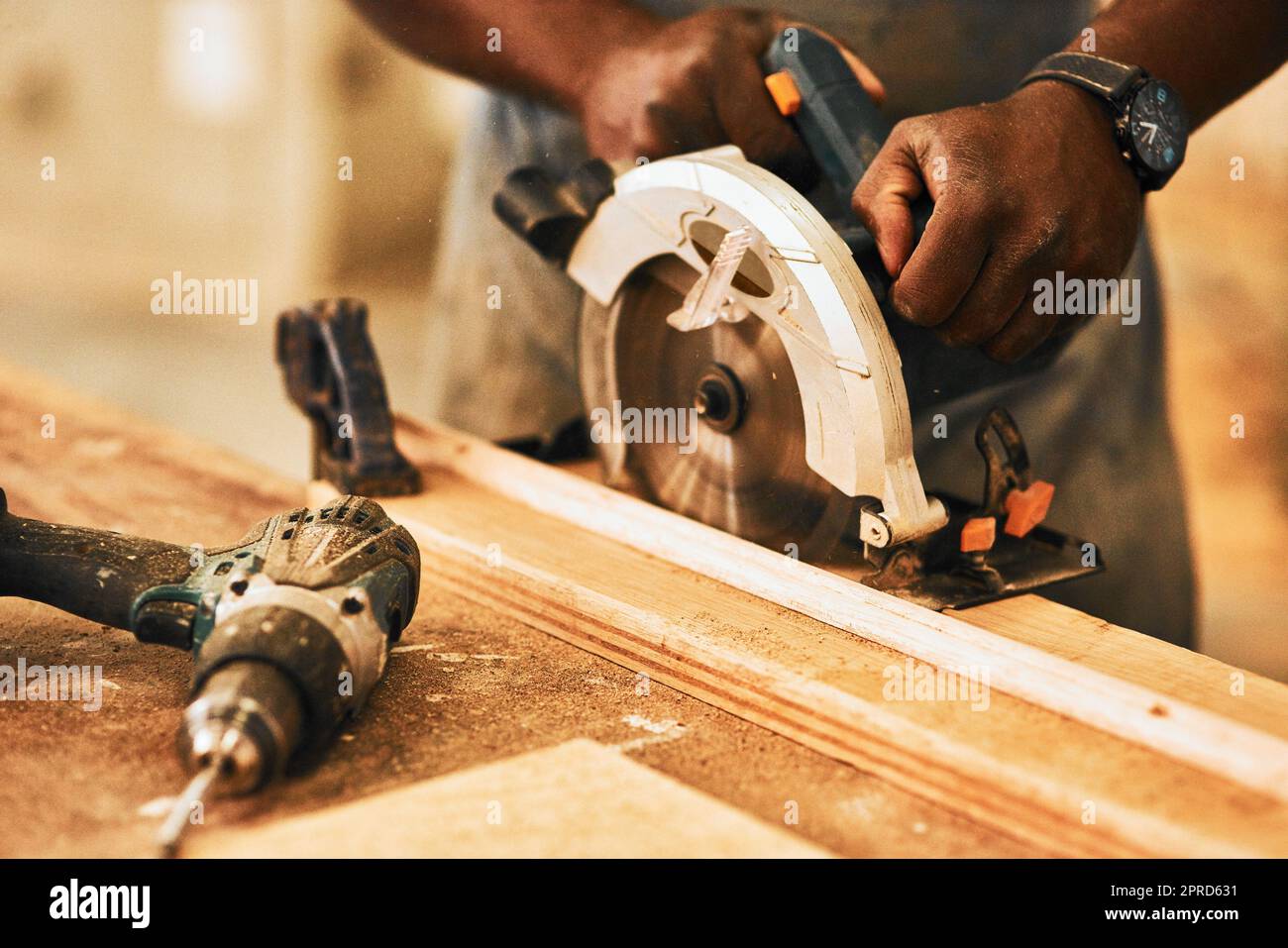 Deja conseguir el corte. Un carpintero irreconocible usando una sierra circular para cortar madera dentro de un taller. Foto de stock