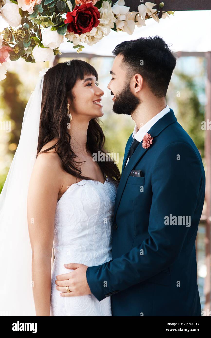 Eres mi costilla que falta. Una pareja joven y cariñosa, sonriendo unos a otros mientras permanecía al aire libre el día de su boda. Foto de stock