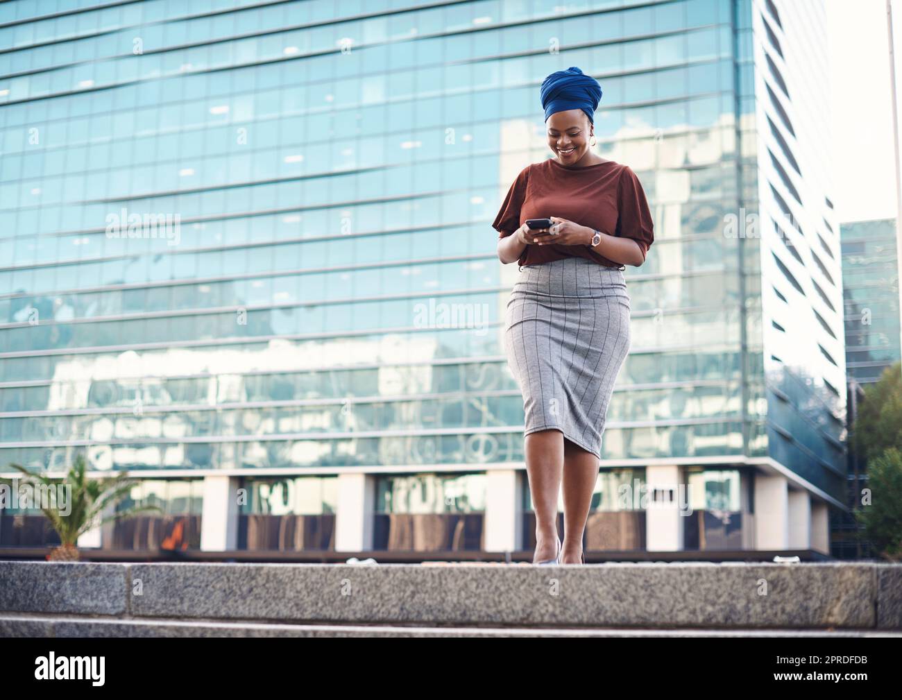 Ya es hora de que se ponga en el centro de atención de la empresa: Una joven empresaria que utilice un smartphone con un fondo urbano. Foto de stock