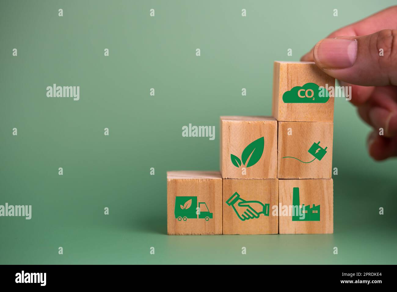 Mano sosteniendo madera cubo bloque icono CO2 de crédito de carbono y la tecnología ecológica de energía verde sobre fondo verde. Foto de stock