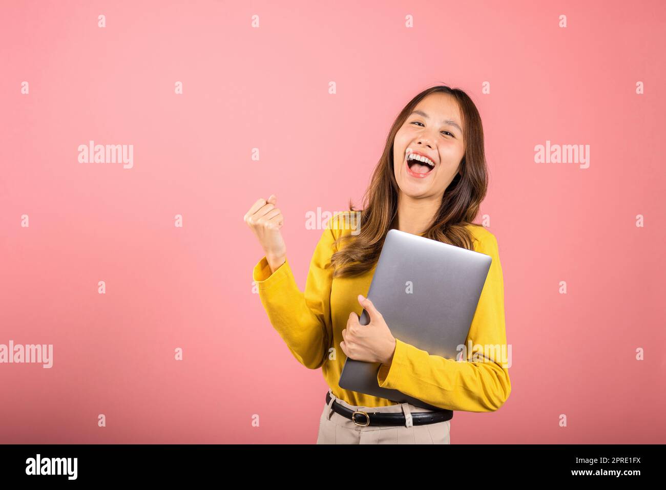 cara sonriente confiada de la mujer que sostiene el ordenador portátil levante la mano y diga sí Foto de stock