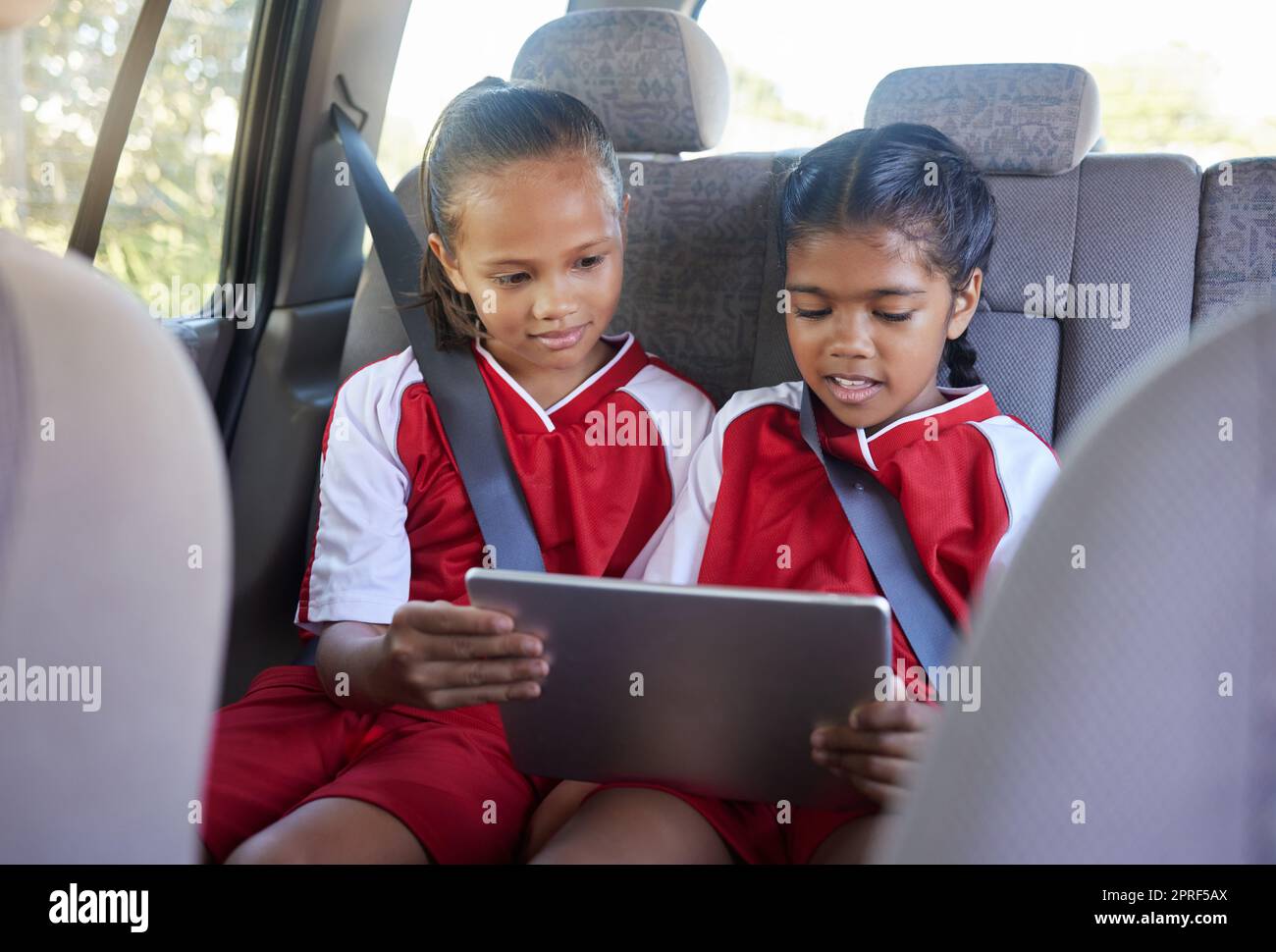 Niños, amigos y tabletas de entretenimiento en el coche, streaming online o  redes sociales. Los niños disfrutan de juegos o aplicaciones mientras se  relajan en el asiento de la pantalla táctil Fotografía