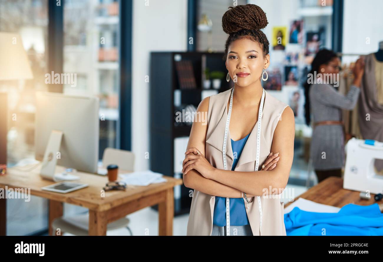 Ella tiene un buen sentido para los negocios también. Una joven diseñadora de moda posando en su taller. Foto de stock