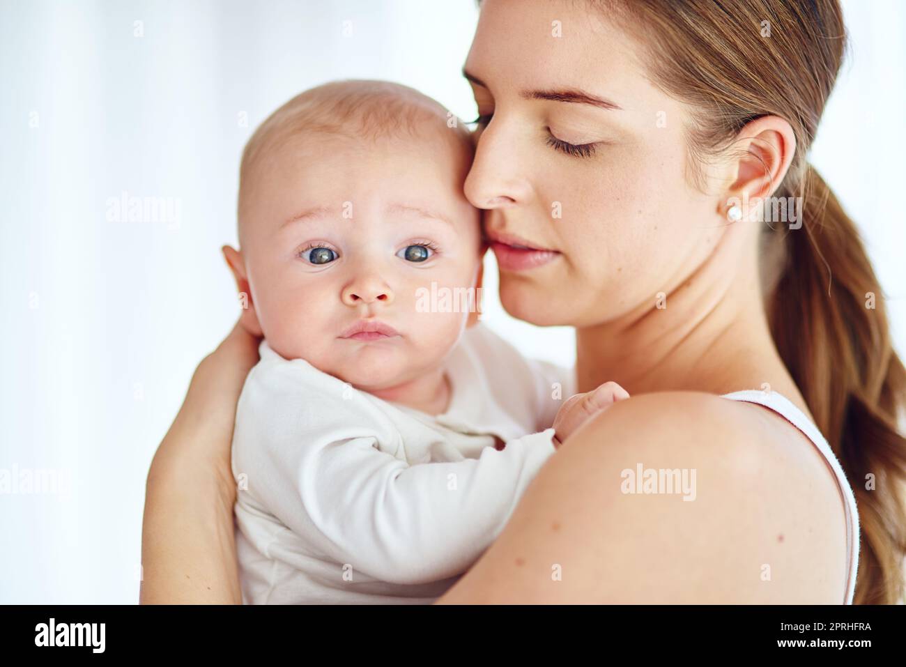 Protegiendo a su pequeño príncipe. Una madre amorosa que lleva a su bebé en casa. Foto de stock