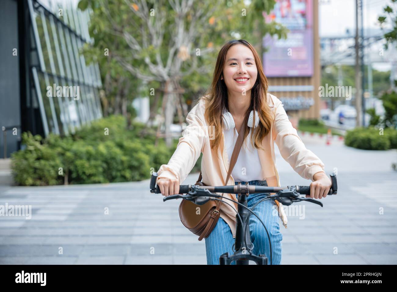 Feliz mujer joven asiática en bicicleta en la calle al aire libre cerca del  edificio de la ciudad, Retrato de la sonrisa estilo de vida de las mujeres utilizar  bicicleta de montaña