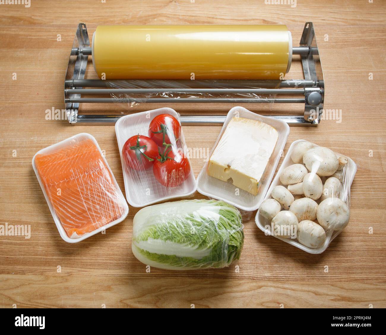 Tomates, champiñones, queso, filetes de salmón y col china se envuelven en film  transparente para un mejor almacenamiento. Rollo de película de alimentos transparente  para embalaje Fotografía de stock - Alamy