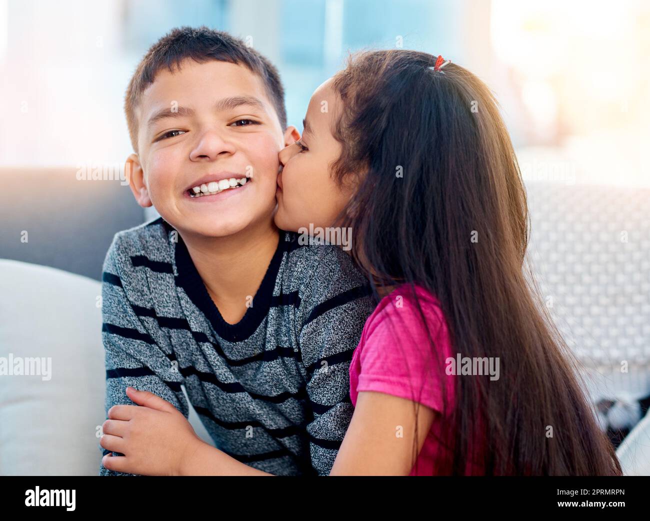 Grandes besos en la mejilla para su hermano mayor. una niña adorable besando a su hermano mayor en la mejilla en casa Foto de stock