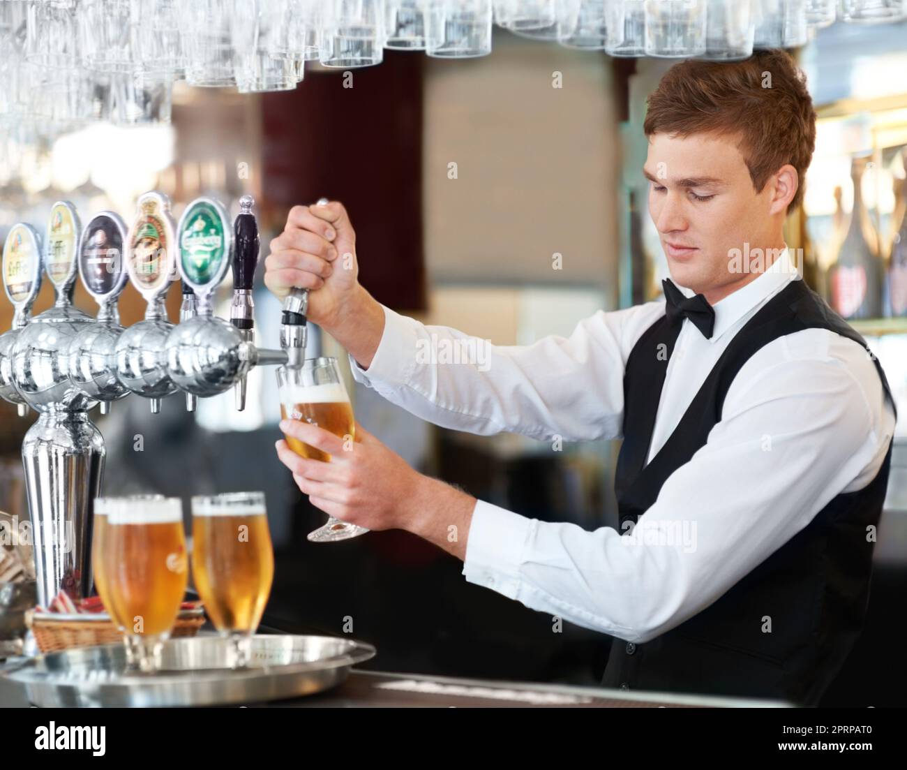 Disfrutando de mi primer día en el trabajo. Guapo joven barman tiende a un  cliente mientras vierte cuatro corrientes de cerveza Fotografía de stock -  Alamy