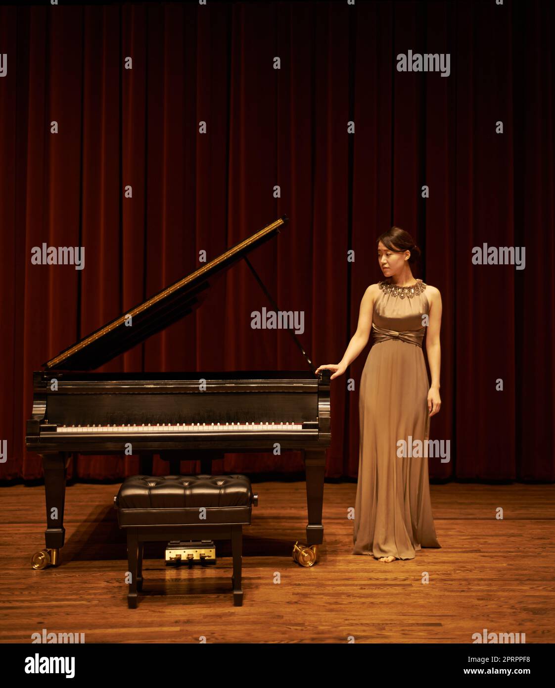 Sólo ella y su compañera de interpretación. Una joven que está al lado de su piano al final de un concierto musical. Foto de stock