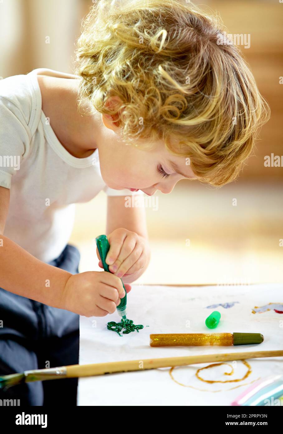 Obra maestra en la elaboración. Un adorable niño haciendo un lío mientras pintaba. Foto de stock