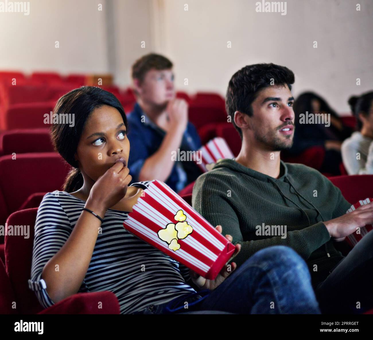 Déjate cautivar por las grandes películas. Gente viendo una película de suspenso en un cine. Foto de stock