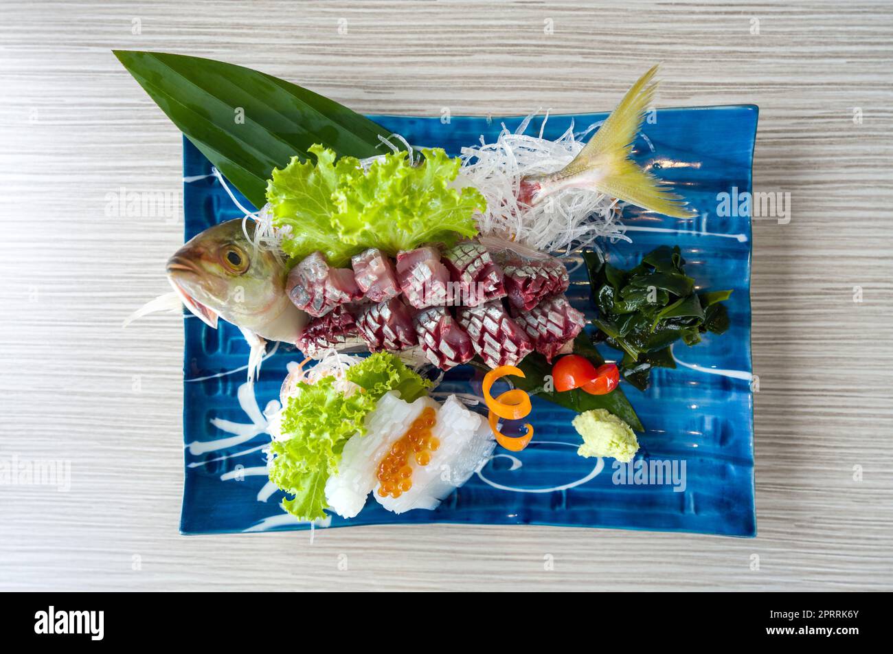Aji Sashimi, jurel fresco en rodajas servido con Ika y Salmón Roe decorado con lechuga verde y rábano rallado. Buffet de cocina japonesa. Foto de stock