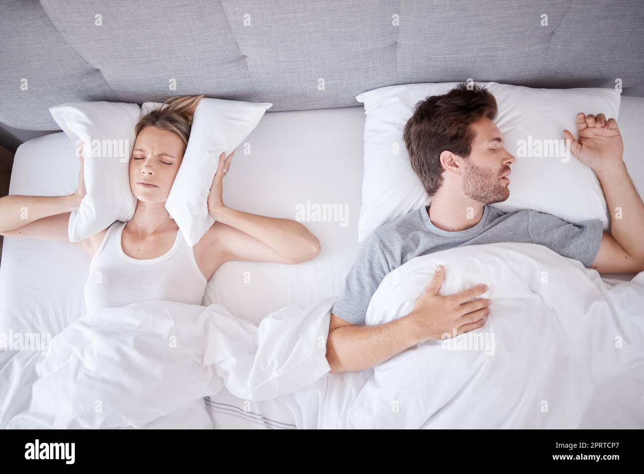 Dormir, roncar y esposa con almohada en las orejas para detener el ruido  del marido en la cama con problema de sueño. Insomnio, frustración y estrés  con la mujer cansada en el