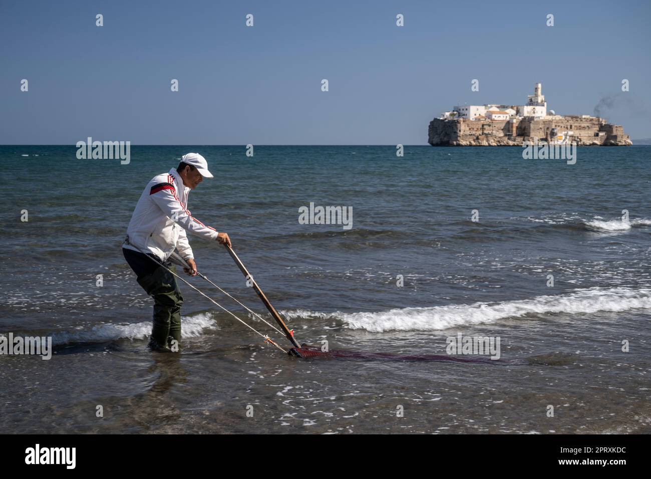 Hombre recogiendo conchas en la playa de Tayeth frente al Peñón de Al Hoceima. La isla es territorio español frente a la costa de Marruecos Foto de stock