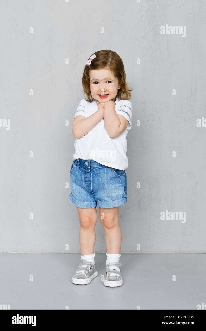 Niña de dos años en blanco pantalón corto y pantalón corto pantalones  vaqueros posando en el estudio Fotografía de stock - Alamy