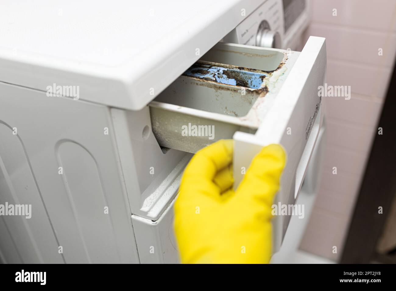 Detergente en polvo en el cajón dispensador de jabón de una lavadora de  carga frontal y un womans mano con un detergente en polvo cuchara de  medición Fotografía de stock - Alamy