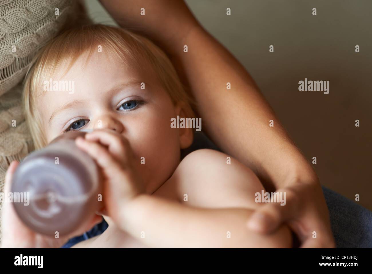 Bebé de 6 meses bebe agua de un biberón, acostado en la cama. bebe feliz y  alegre