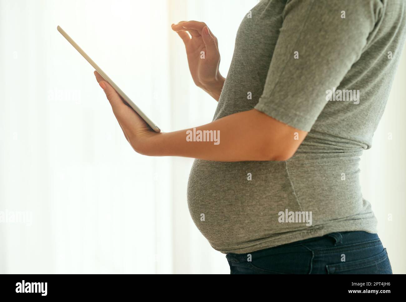 Almacenando todos sus recuerdos de embarazo. una mujer embarazada usando su  tableta digital en casa Fotografía de stock - Alamy